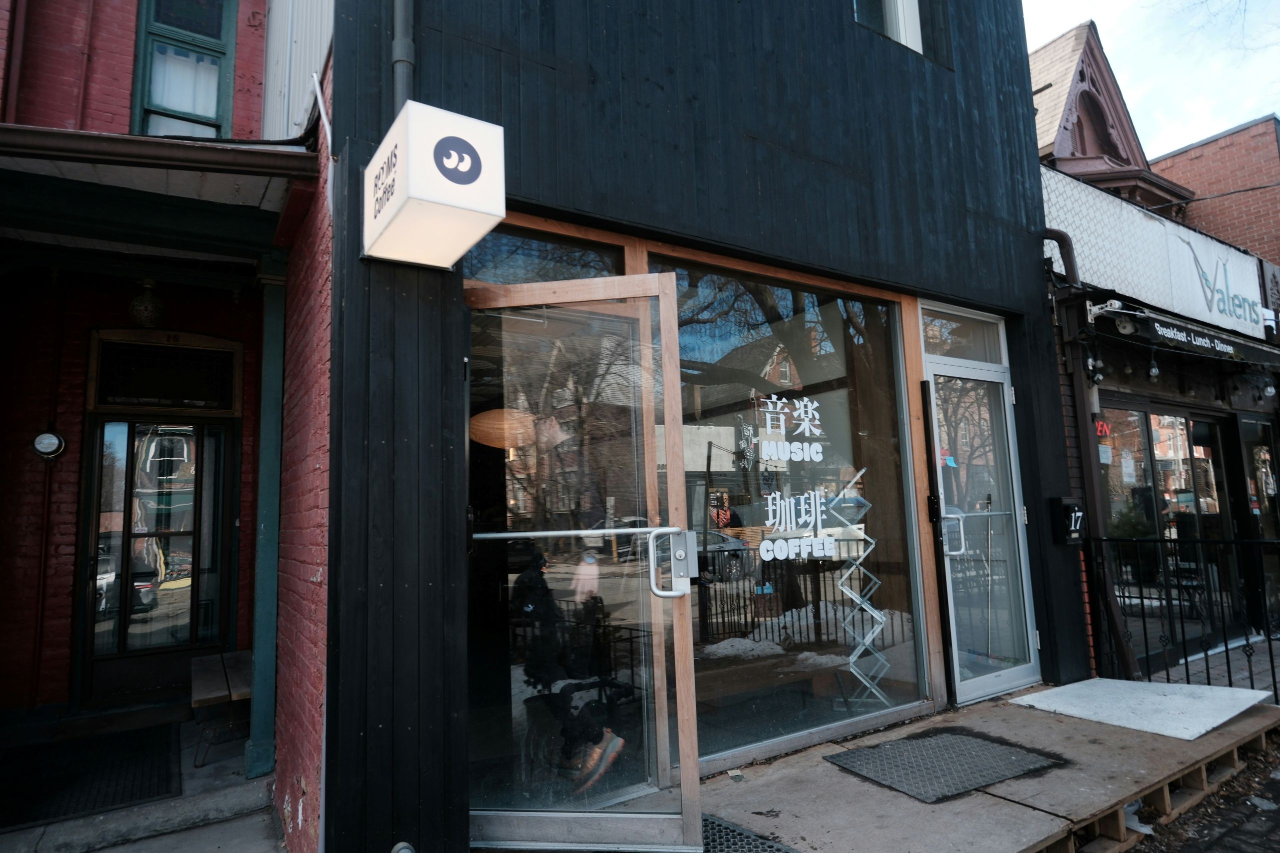 A modern black building with a glowing sign that reads ROOMS COFFEE and Japanese characters for music and coffee.